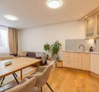 Nyaraló apartman belső tere kanapéval, konyhával és fa dekorációjú padlóval.