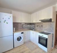 Konyha egy egyszobás lakásban fehér szekrényekkel és fa dekorációjú padlóval.