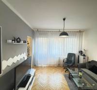 Nappali egy kétszobás lakásban, fa hatású padlóval és stílusos bútorokkal.