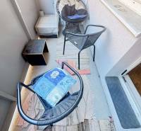 Erkély bútorokkal a kétszobás lakásban, a dekoratív székek és szőnyeg otthonosságot kölcsönöznek.