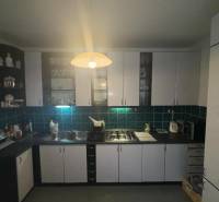 Konyha egy kétszobás lakásban fekete munkalappal és fehér szekrényekkel.