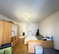 Hálószoba egy kétszobás lakásban fa mintázatú padlóval és tárolóhellyel.