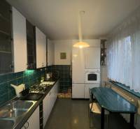 Konyha egy kétszobás lakásban sötétzöld csempékkel és fa dekoros padlóval.