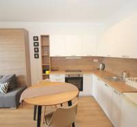 Kompakt konyha és nappali rész fa dekor padlóval egy egyszobás lakásban.