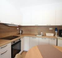 Beépített készülékekkel és fa dekorációval ellátott konyha egy egyszobás lakásban.