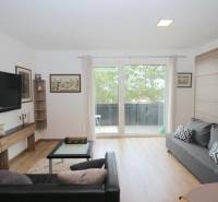 Nappali egy egyszobás lakásban, TV-vel, kanapékkal és fa dekorációjú padlóval.