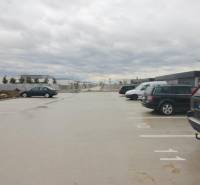 Parkoló a Broskyňová utcában, Rovinka városában, autókkal és lakóépületekkel a háttérben.