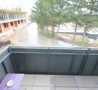 Félkész épületek és fák a Broskyňová utcában Rovinkán, kilátás egy egyszobás lakásból.