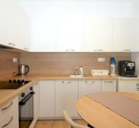 Fehér konyha fa dekorációval az egyszobás lakásban, háztartási gépekkel.