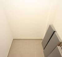 Kis tárolóhely egy egyszobás lakásban csempével és fehér falakkal.