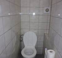 Háromszobás lakás WC-je csempével és szellőzőnyílással.