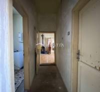 Keskeny folyosó vezet egy szobába, amelynek padlója fa dekorációval van ellátva egy családi házban.