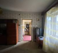 Egy szoba családi házban retro bútorokkal, régi televízió, ablak virágos függönyökkel.