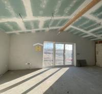 Családi ház befejezetlen szobája ablakokkal és kilátással a kertre.