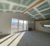 Családi ház belső tere betonpadlóval és nagy ablakkal.