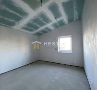 Szoba egy családi házban fehér falakkal és ablakkal.