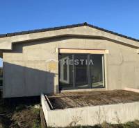 Családi ház Sekule városában, befejezetlen terasszal és nagy üvegajtókkal.