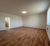 Szoba egy családi házban fa dekoros padlóval és fehér falakkal.