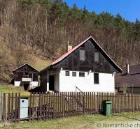 Ház Moštenicában, erdőkkel körülvéve, kerítéssel és szemetes a kertben.