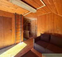 A fahatású burkolatokkal és padlóval rendelkező házikó belseje, kanapéval és létrával.