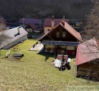 Házikó Moštenicában, gyep és fák veszik körül.