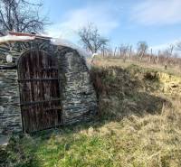 Kőbejárat a pincéhez, amelyet természet vesz körül a szőlőskertekben, közel Aranyosmaróthoz.