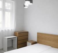 Hálószoba fából készült bútorokkal és függő világítással egy kétszobás lakásban.