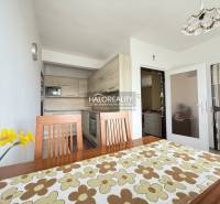 Világos konyha családi házban, fa bútorokkal és dekoratív asztalterítővel.