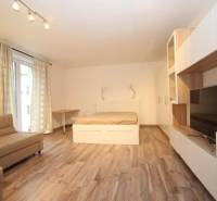 Nappali zóna egyszobás lakásban ággyal és fa dekor padlóval.