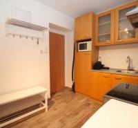 Konyha egy egyszobás lakásban konyhabútorral, háztartási gépekkel és fa dekorációjú padlóval.