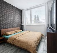 Hálószoba egy kétszobás lakásban geometrikus tapétával és fa dekorációjú padlóval.