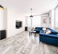 Nappali egy kétszobás lakásban kék kanapéval és fa dekorációjú padlóval.