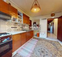 Konyha családi házban szőnyeggel, gáztűzhellyel és fa szekrényekkel.