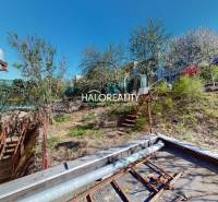 Családi ház Rimaszombatban, egy lejtős kert mellett, fákkal.