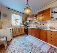 Konyha családi házban fa szekrényekkel, szőnyeggel és függő lámpával.