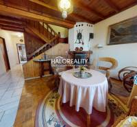 Családi ház fa mintázatú padlóval, rattan bútorokkal, kandallóval, szőnyeggel, fa mennyezettel.