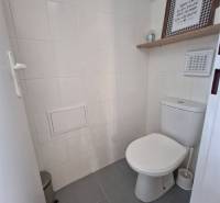 Fehér csempés mosdó dekoratív polccal kereskedelmi helyiségben.