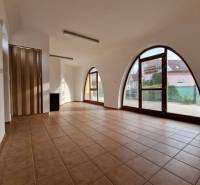 Üzlethelyiségek belső tere nagy boltíves ablakokkal, csempével és faajtókkal.