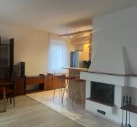 Konyha és nappali kandallóval és bárpulttal, fa hatású padlóval.