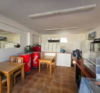 Vendéglátóhelyiség fa dekorációjú padlóval, asztalokkal és hűtőszekrényekkel.