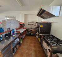 Professzionális készülékekkel és készletekkel felszerelt gasztronómiai helyiség konyhája fa dekor padlón.