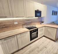 Konyha fa dekor padlóval egy kétszobás lakásban, világos fa szekrényekkel és beépített készülékekkel.