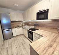 Konyha egy kétszobás lakásban, fa dekoros padlóval és világos bútorokkal.