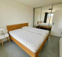 3 szobás lakás ággyal, szekrénnyel, éjjeliszekrénnyel és tükrös ajtókkal.