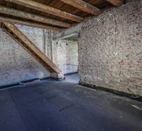 Téglafalak és lépcsők a családi ház tetőterében, fa dekoros padlóval.