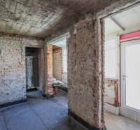 Családi ház befejezetlen téglafalakkal és fehér ajtókkal, betonpadlóval.