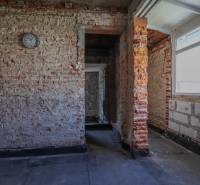 Vakolatlan téglafalak és egyszerű belső tér egy családi házban ablakkal.