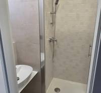 Fürdőszoba modern zuhanyzóval és mosdóval a garzonlakásban.