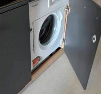 Beépített mosógép szürke ajtók mögött egy garzonlakásban egyszerű padlóval.