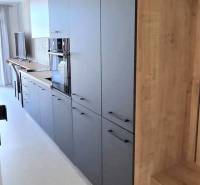 Konyhapult garzonlakásban sötét szekrényekkel és világos, fa mintázatú padlóval.